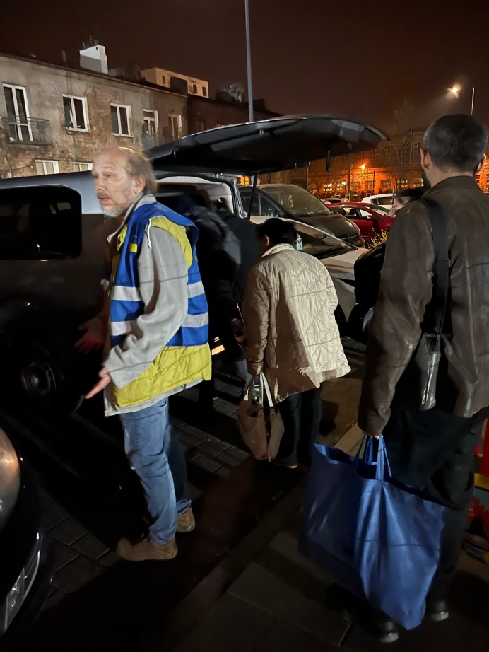 Volunteers helping people load their luggage from the Eastern Rail Station into my van to go to the Expo Center, a large shelter. It was very loud and busy when we checked them in at 10PM.